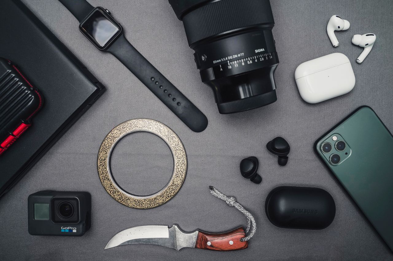 Service Flat lay of tech gadgets and personal accessories including camera and smartwatch.