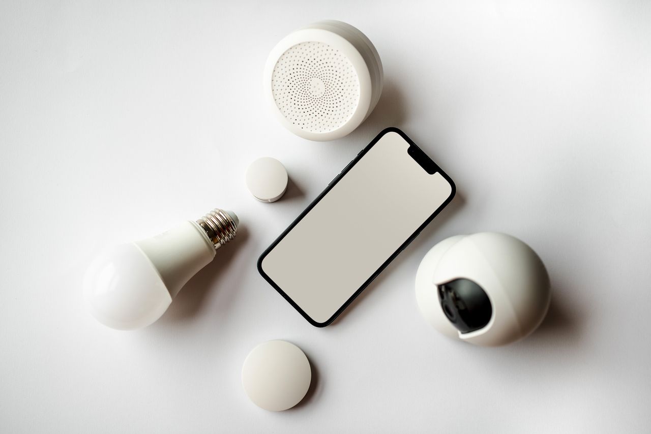 Service Flat lay of smartphone and smart home devices on a white backdrop, showcasing modern technology.