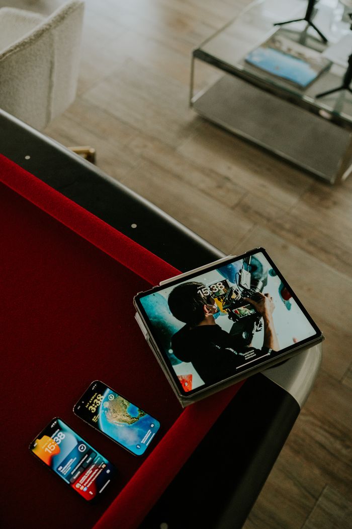 Service A tablet and smartphones displayed on a pool table in a stylish living room setting.